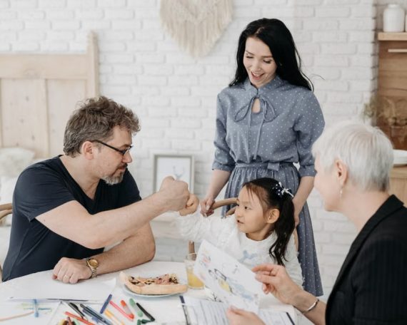 Child with foster parents and a social worker discussing adoption at home.