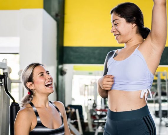 Two women in activewear sharing a joyful moment during a gym workout session.